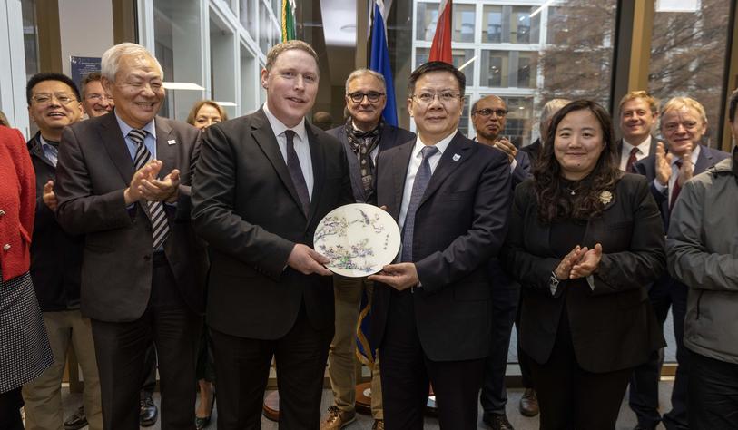 A group of people pose for a photo with two people holding a decorative plate